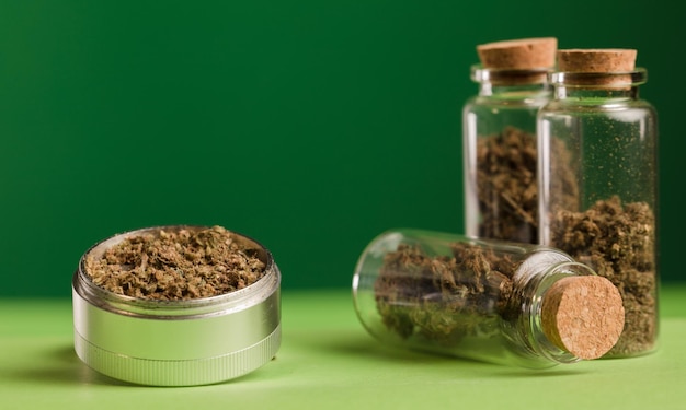 Premium Photo | Marijuana on grinder glass jars on table with dark ...