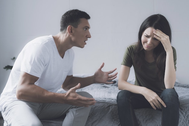 Premium Photo | Married couple sitting on gray bed and arguing