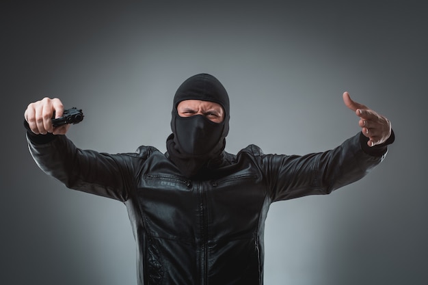 Premium Photo Masked Robber With Gun Looking Into The Camera