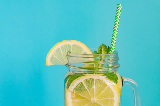 背景色が水色のレモン ミント 紙ストローで自家製レモネードのメイソンジャーガラス 夏の爽やかな飲み物 プレミアム写真
