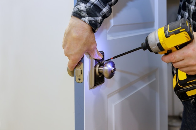 Master with screwdriver installs access the room door new lock in house. Premium Photo