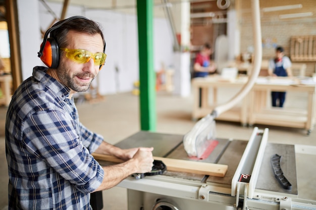 Premium Photo | Mature carpenter using machines in workshop