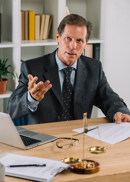 Free Photo | Mature male lawyer sitting in the courtroom giving advice