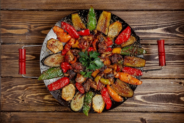 Meat sage with potatoes bell pepper and eggplant cooked on charcoal top view Free Photo