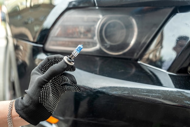 Premium Photo | Mechanic hand holding halogen light bulb near on car ...