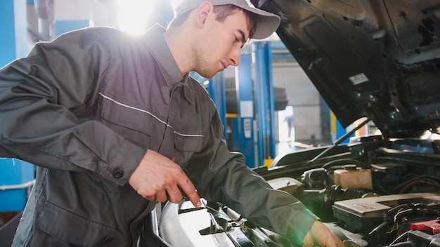 Premium Photo | Mechanic in overalls checks level of engine oil in the ...