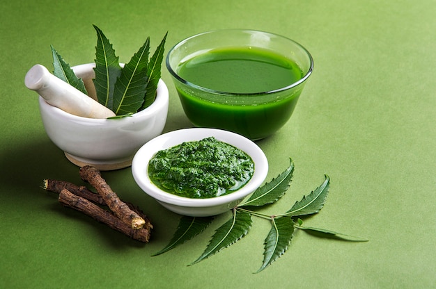 Medicinal neem leaves in mortar and pestle with neem paste, juice and twigs Premium Photo