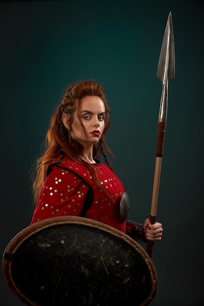 Medieval female warrior posing with spear, shield. Free Photo
