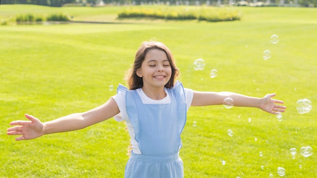 Medium shot cheerful girl playing with soap bubbles Free Photo
