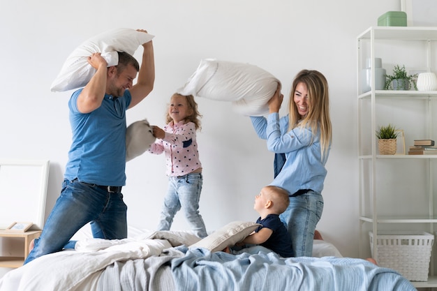 Medium shot family members fighting with pillows Free Photo