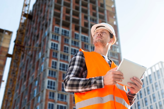 Medium shot low angle view of engineer holding tablet Free Photo