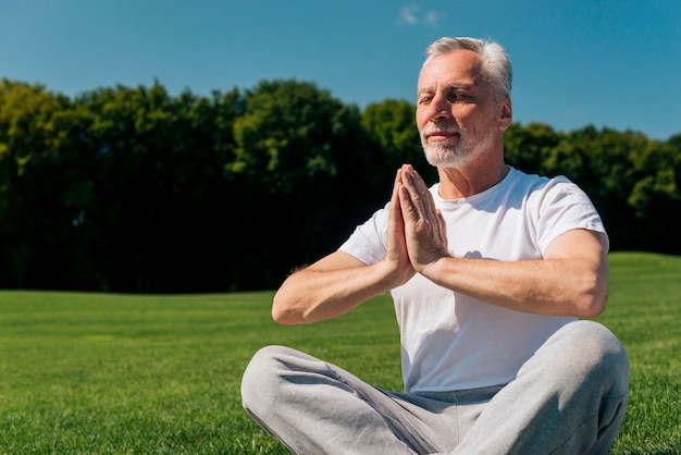 Medium shot old man meditating in nature Photo | Free Download