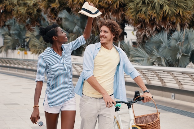 Medium shot of young couple walking with bicycle in the summer Free Photo