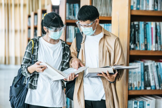 Men and women wearing masks stand and read in the library ...