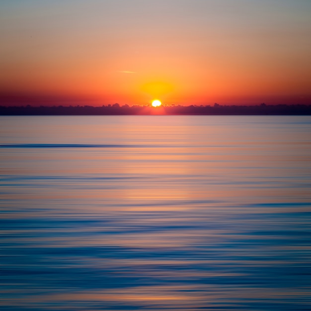 澄んだ青い海に沈む夕日 無料の写真