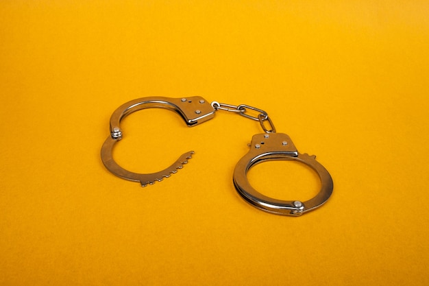 Premium Photo | Metal handcuffs on a yellow background, concept of arrest.