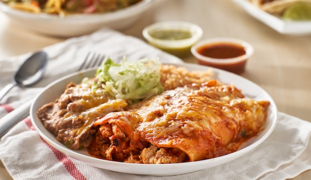 Premium Photo | Mexican enchilada platter with red sauce, fried beans ...