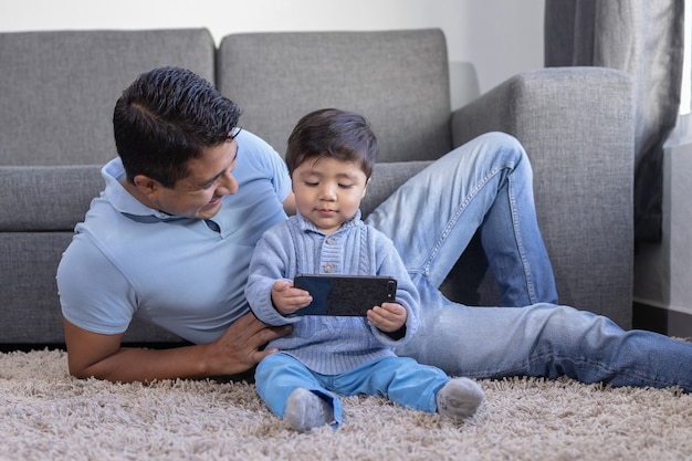 Premium Photo | Mexican father and son looking at phone on carpet at home