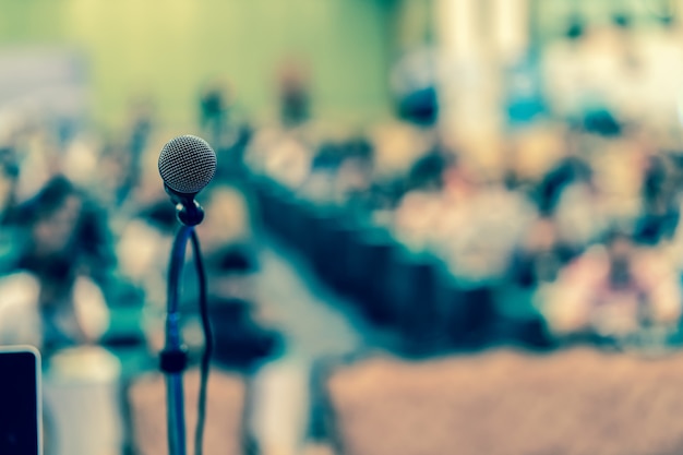 Microphone over the abstract blurred photo of conference hall or seminar room Premium Photo