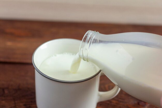 Premium Photo | Milk from the bottle is poured into a mug.close-up.