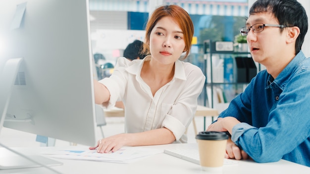 Millennial group of young asia businessman and businesswoman in small modern urban office. japanese male boss supervisor teaching intern or new employee korean girl helping with difficult assignment. Free Photo