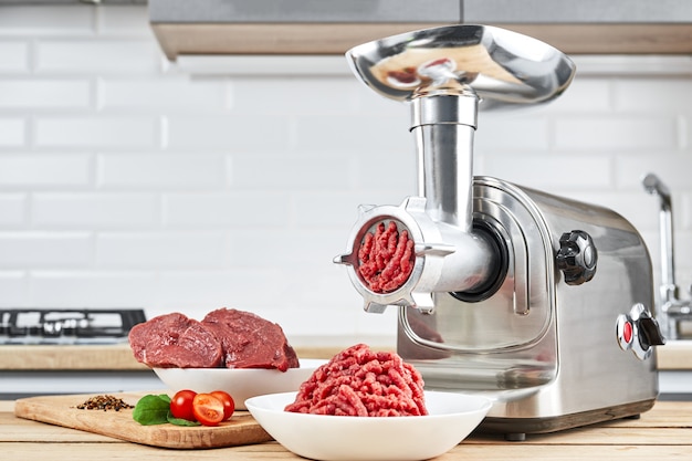 Mince with electric meat grinder in the kitchen Premium Photo