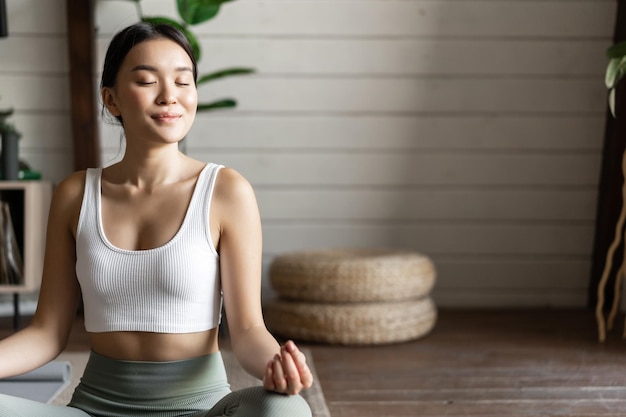 Концепция внимательности и медитации молодая азиатская женщина делает тренировку дома медитацией