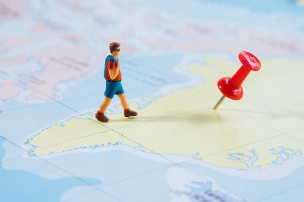Mini figure traveler with red pushpin and a map travel concept Free Photo