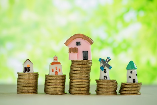Mini house on stack of coins with green blur. Free Photo