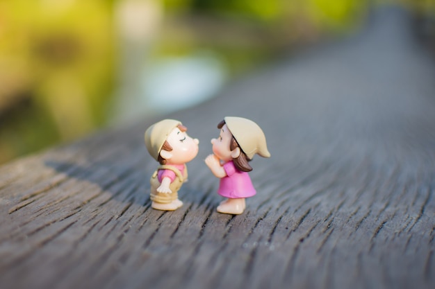 ミニチュアカップルは木製の地面にキスを愛する プレミアム写真