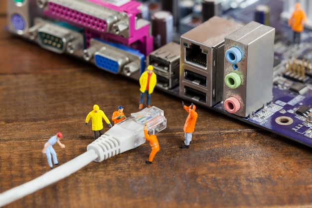 Miniature engineer and worker plug-in lan cable to computer Free Photo