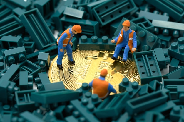 Miniature people construction worker digs a gold bit coin Premium Photo
