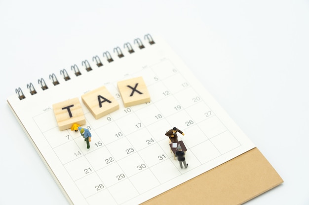 Miniature people pay queue annual income (tax) for the year on calendar. Premium Photo