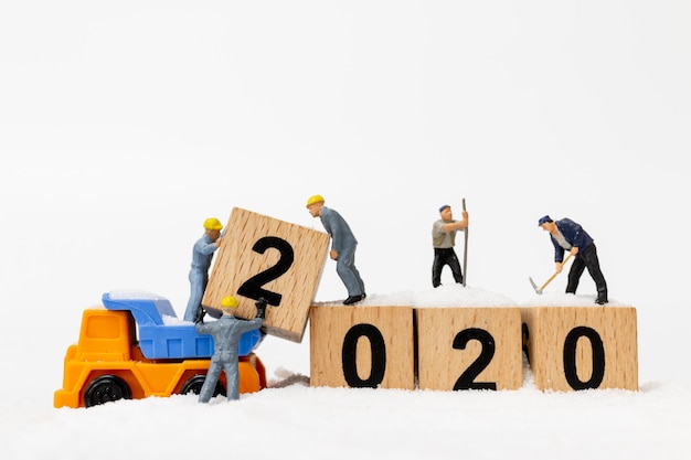 Miniature people, worker team create wooden block number 2020 Premium Photo