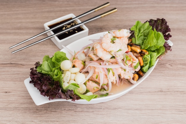 Mixed ceviche with soy sauce on a wooden table Premium Photo