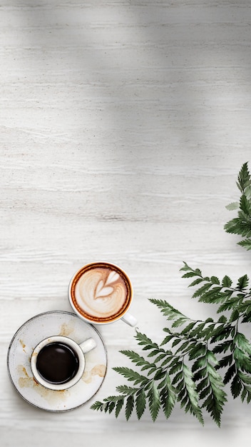 白い木製の織り目加工の壁紙に葉と混合コーヒーカップ 無料の写真