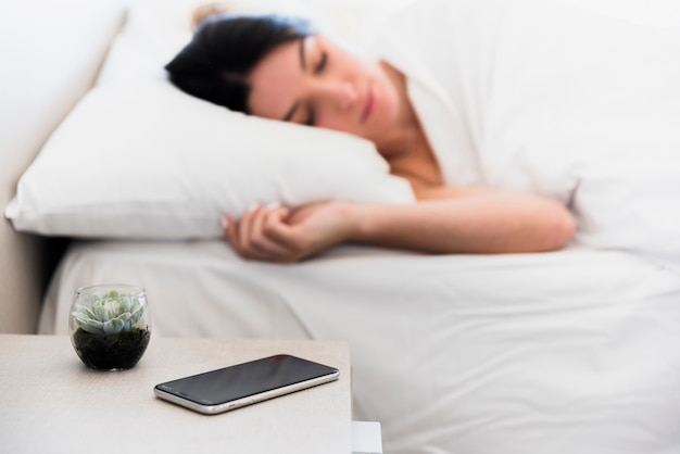 Premium Photo Mobile Phone And Cactus Plant On Bedside Table Near Young Woman Sleeping In Bed