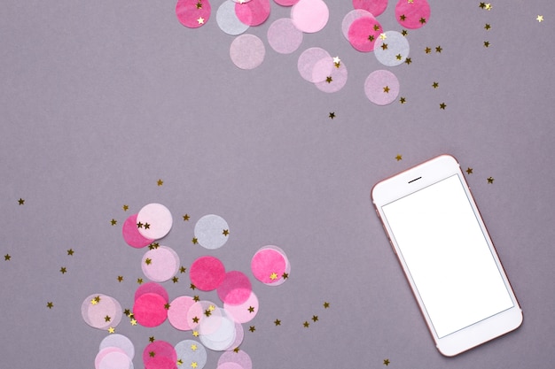 Mobile phone mock up and pink confetti with gold stars on gray Premium Photo