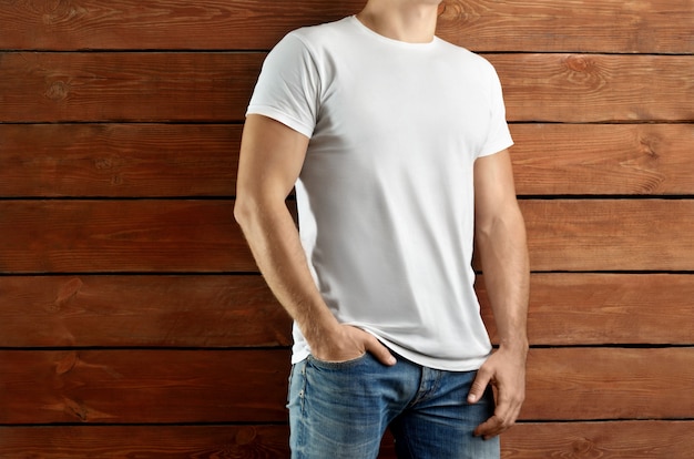 Premium Photo Mockup Clothes Brawny Slim Man In A White T Shirt And Blue Jeans Standing On A Brown Wooden Studio Background Template Ready For You Showcase