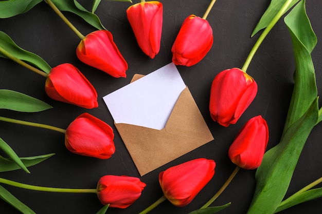 Download Mockup of fresh red tulips bouquet and white blank greeting card in kraft envelope | Premium Photo