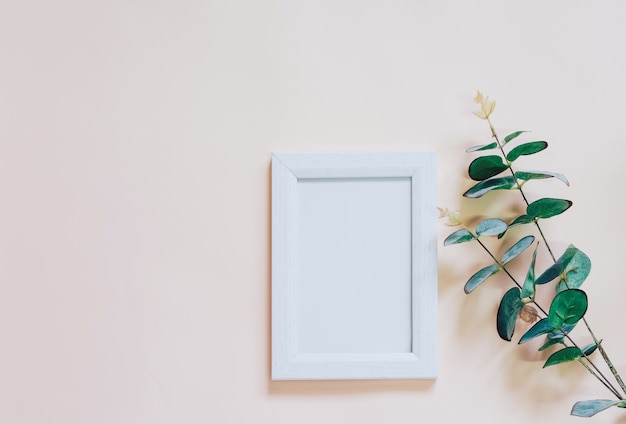 Mockup of blank photo frame with green plant on yellow 
