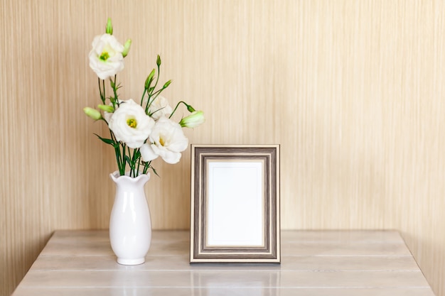 フォトフレーム コピースペースのある木製のテーブルの上に花瓶に白い花ユーストマまたはトルコギキョウのモックアップ プレミアム写真