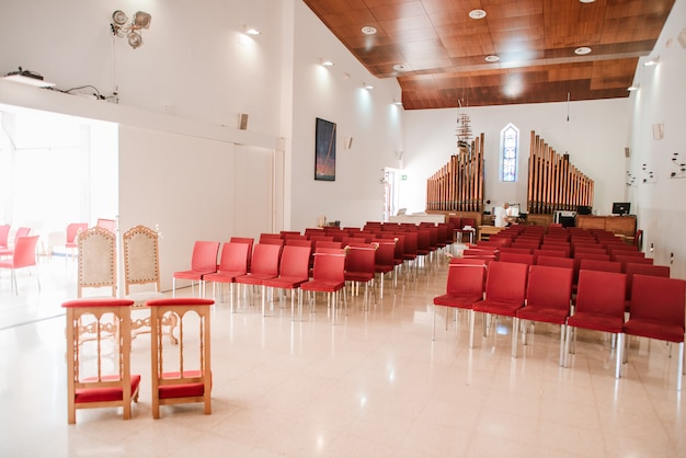 Modern Catholic Church Hall With Red Chairs And Organ Premium Photo