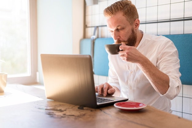 Free Photo | Modern man working on his laptop while drinking coffee