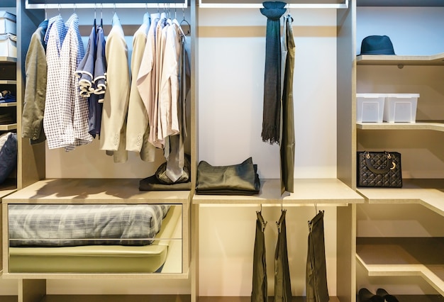 Modern Wooden Wardrobe With Clothes Hanging On Rail In Walk In