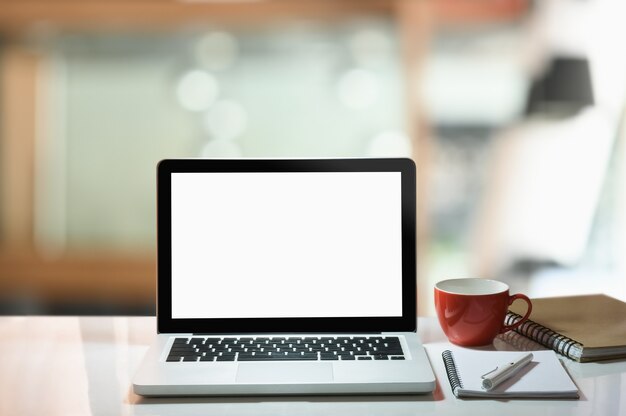 モダンなワークスペース 白い画面のノートパソコン コーヒーカップ 白いテーブルのノートブック プレミアム写真