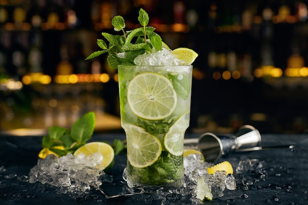 Mojito cocktail, against the surface of bottles, on the bar, with bar attributes Premium Photo
