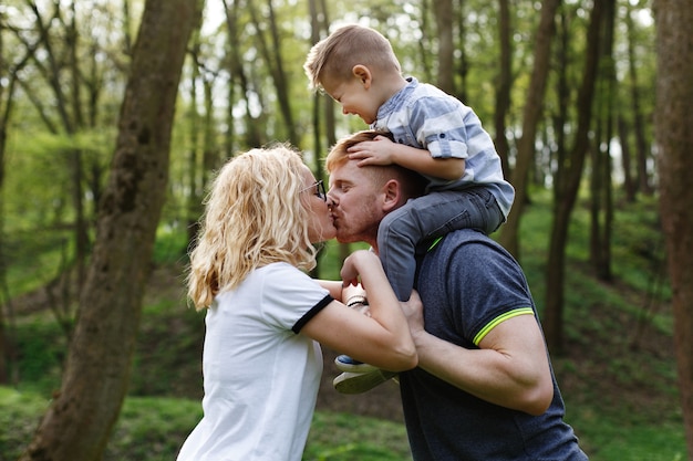 Mom And Dad Kiss While Their Little Son Closes His Eyes Free Photo