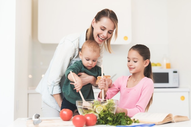 Mom daughter and little baby prepare a salad. Premium Photo