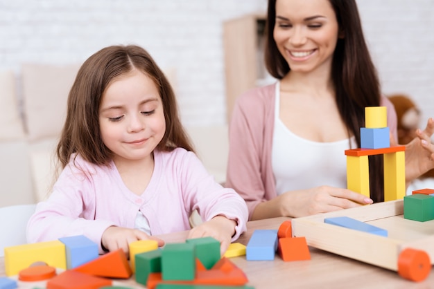Premium Photo | Mom and daughter play together with wooden cubes.